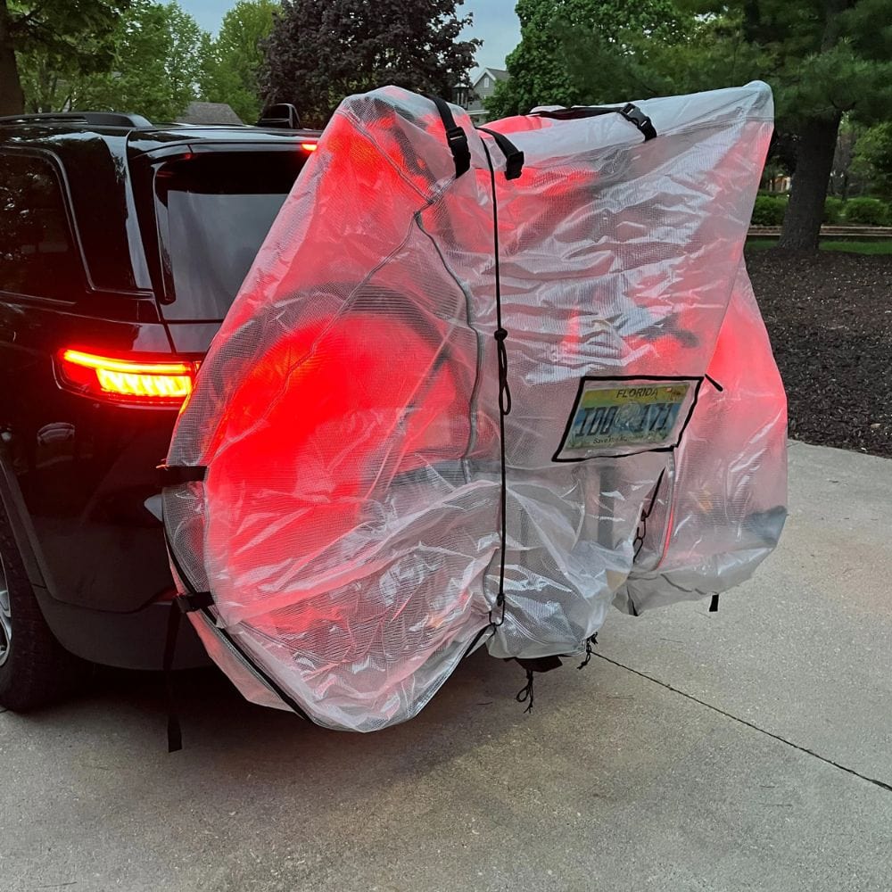 Bicycle with a transparent cover attached to a car, with a visible license plate.