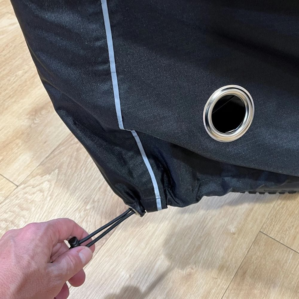 Close-up of a black jacket with a grommet on a wooden floor.